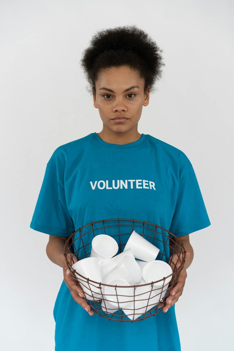 African American volunteer holding a basket of disposable cups, promoting environmental conservation.