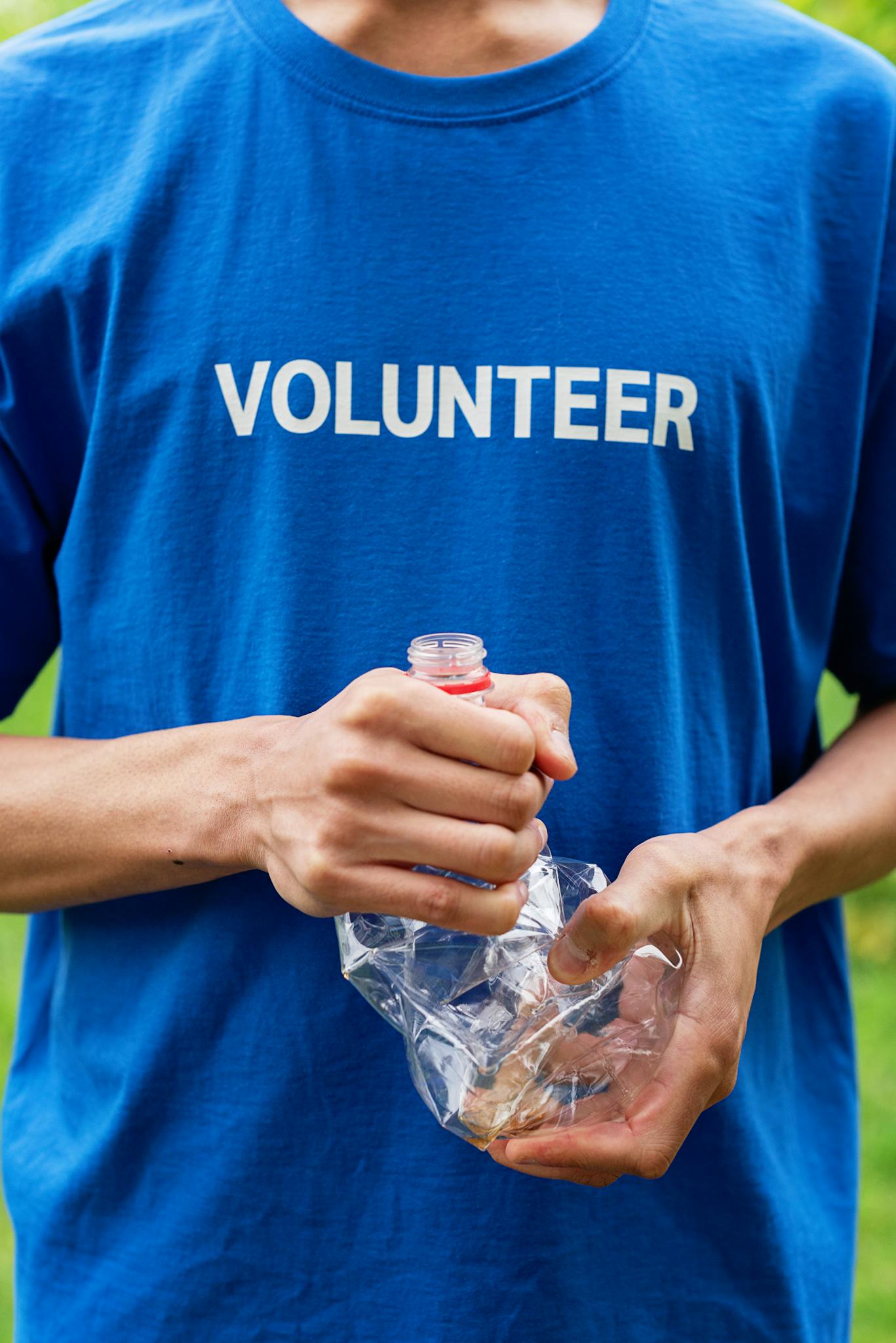 Close-up of a volunteer crushing a plastic bottle to promote recycling and environmental awareness.