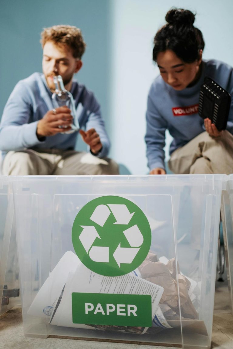 Two volunteers sorting recyclables like paper and glass with a recycling bin.