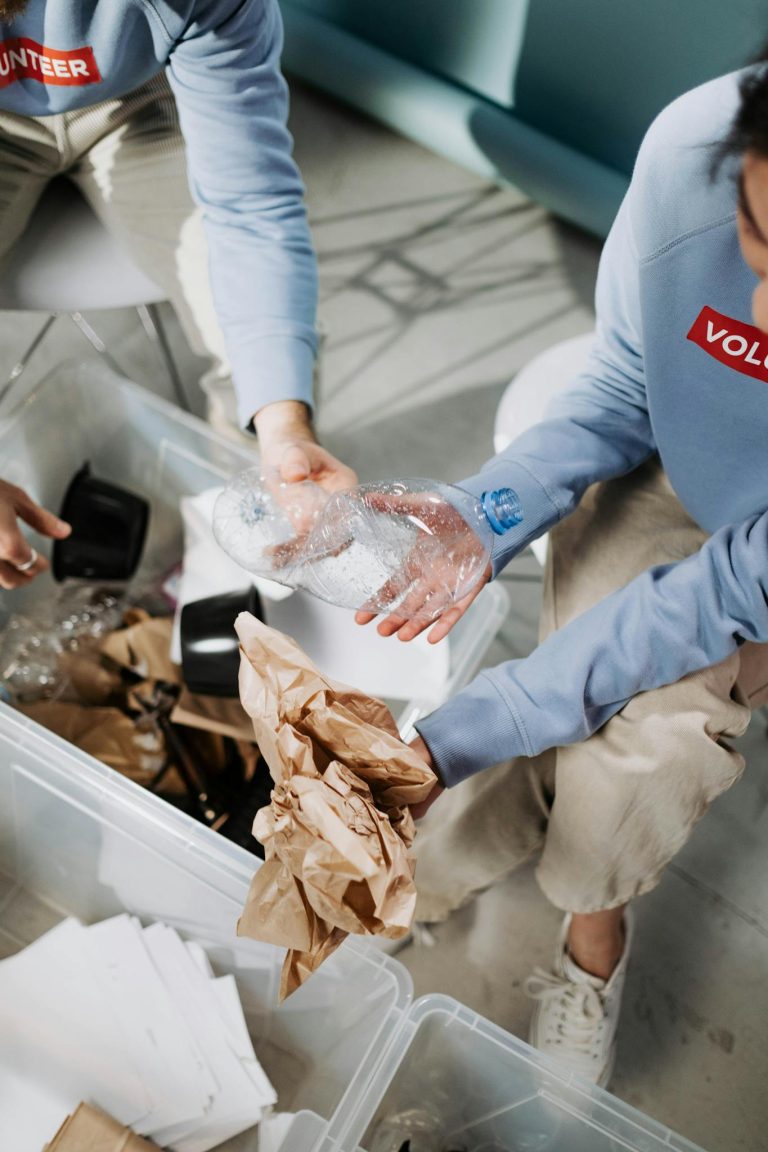 Volunteers in blue shirts sorting recyclable materials like paper and plastic.